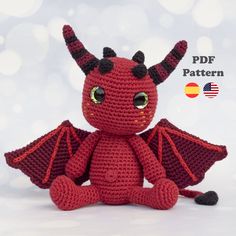 a crocheted red dragon stuffed animal sitting on top of a white tablecloth