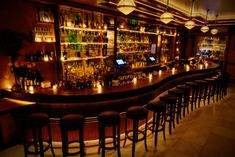 a dimly lit bar with lots of bottles and stools