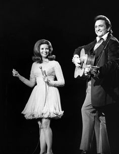 a man and woman standing next to each other with guitars in their hands on stage