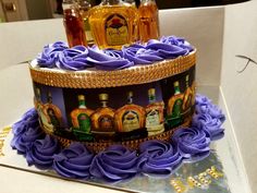 there is a cake decorated with liquor bottles and flowers on the counter top, as well as purple icing