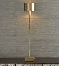 a lamp that is sitting on top of a wooden table in front of a wall