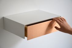 a person is holding an open box on the wall with their hand and it's opening