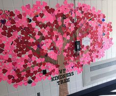 a bulletin board with pink hearts on it and a tree made out of small pieces of paper