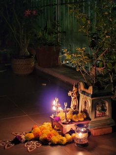 candles and flowers on the ground next to a statue with an image of jesus in it