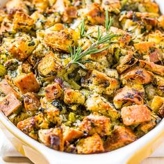 a casserole dish filled with stuffing and topped with a sprig of rosemary