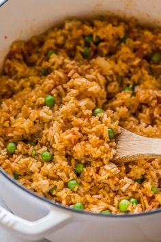 rice and peas are mixed together in a pot with a wooden spoon on the side