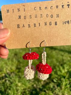 a pair of crocheted red and white earrings hanging from a wooden hanger