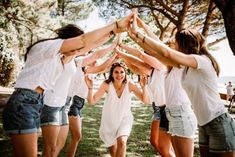 a group of young women holding hands together in a circle with their arms around each other