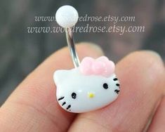 a tiny hello kitty belly ring with a pink bow on it's head, sitting in someones hand