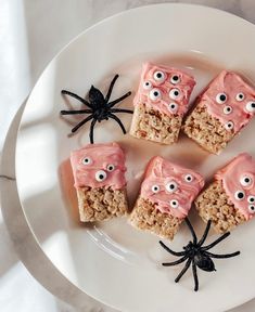 four pieces of rice krispy treats decorated with eyes and spider webs on a white plate