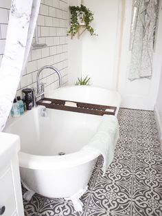 a bath tub sitting under a window next to a sink in a white tiled bathroom