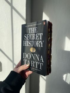 a person holding up a book about the secret history