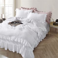 a white bed with ruffled sheets and pillows