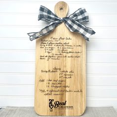 a wooden cutting board with a black and white gingham bow on the front