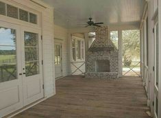 an empty porch with a brick fireplace in the center and french doors on both sides