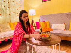 a woman sitting at a table with flowers in a bowl on it's side