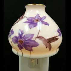 a white vase with purple flowers painted on it