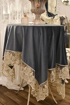 the table is covered with lace and has a vase on it