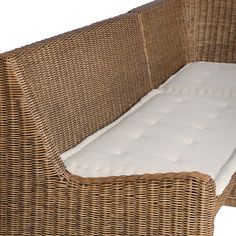 a brown wicker couch with a white mattress on it's backrests