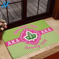 a green and pink door mat with the words akaa aka written on it