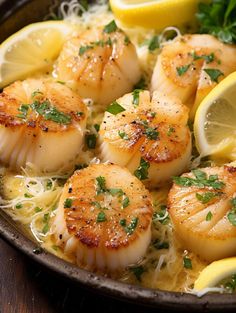 a pan filled with cooked scallops and lemon wedges on top of noodles