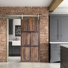 an open door to a kitchen with brick walls and grey cabinets in the back ground