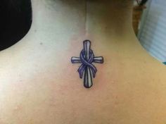 a cross tattoo on the back of a woman's neck, with a ribbon around it