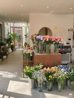 many vases filled with flowers sitting on top of a counter in a room full of windows