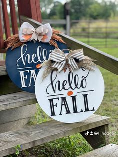 two painted pumpkins sitting on top of a wooden bench next to a fence with the words hello fall