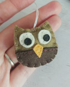 an owl ornament hanging from a string in the palm of someone's hand