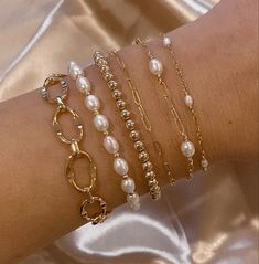 a close up of a person's arm with bracelets and pearls on it