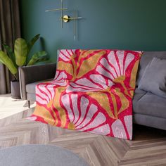 a living room with a gray couch and a red and yellow blanket on top of it