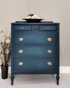 a blue chest of drawers with flowers on top