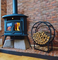 a wood burning stove sitting next to a pile of logs on top of a hard wood floor