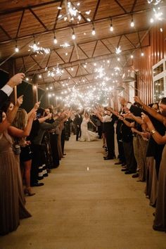 the bride and groom are walking down the aisle with sparklers