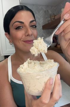 a woman is eating ice cream with a spoon in her hand and smiling at the camera