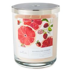 a candle that is filled with pink grapefruits and raspberry slices