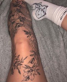 a person laying on a bed with their legs covered by socks and flowers tattooing them