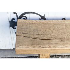 a wooden bench sitting in front of a white building with iron brackets on it's sides