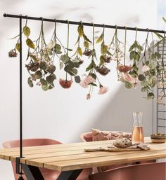 a wooden table topped with pink chairs next to a wall mounted planter filled with flowers