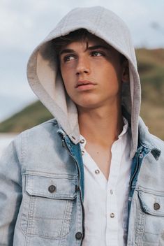 a young man wearing a denim jacket and hoodie