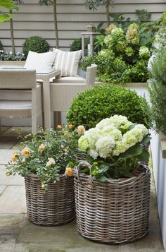 three wicker baskets filled with flowers on a patio