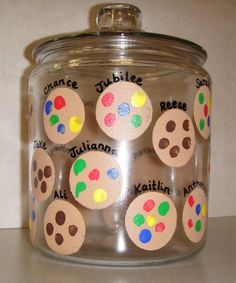 a jar filled with lots of different colored buttons on top of a white counter next to a wall