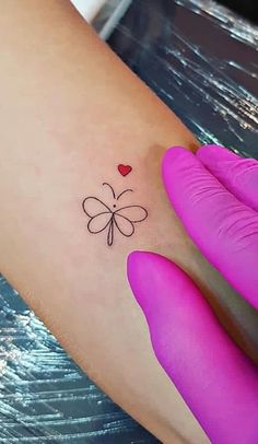 a small butterfly tattoo on the left side of the right arm, with a heart in it's center