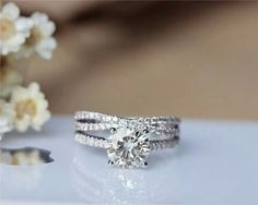 a diamond ring sitting on top of a table next to some flowers and a vase