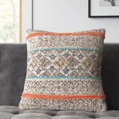 a decorative pillow on a gray couch in a living room with a framed photograph above it