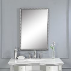 a bathroom vanity with a large mirror above it and a vase on the counter next to it