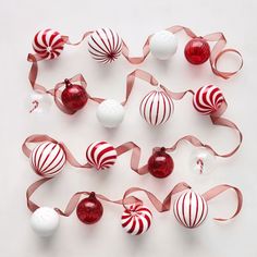 red and white ornaments are arranged on a white surface with pink satin ribbons around them