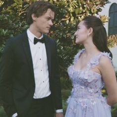 a man in a tuxedo standing next to a woman