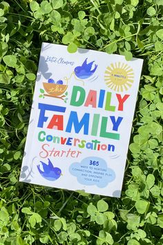 a book sitting in the grass on top of green leaves with an image of a baby bird